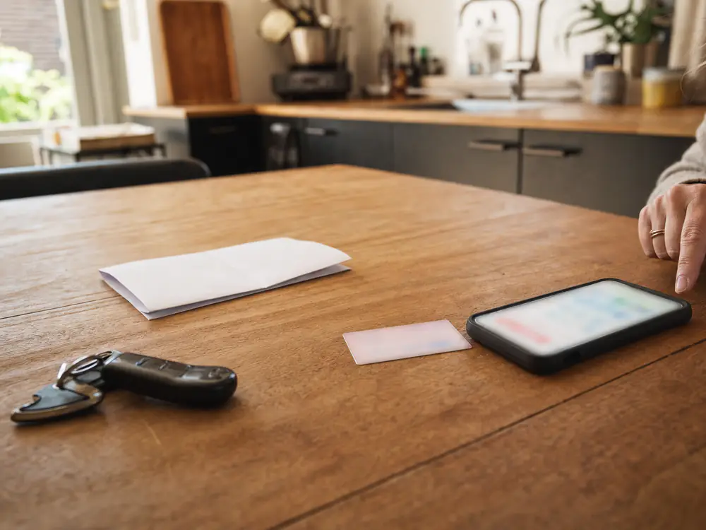 Kentekencard, brief en autosleutel op de keukentafel naast een telefoon