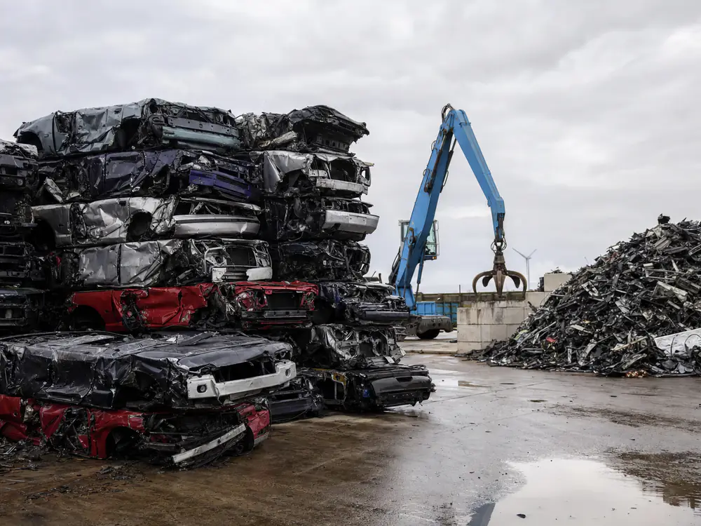 Gestapelde geperste autowrakken en gesorteerd oud ijzer op een recyclingterrein